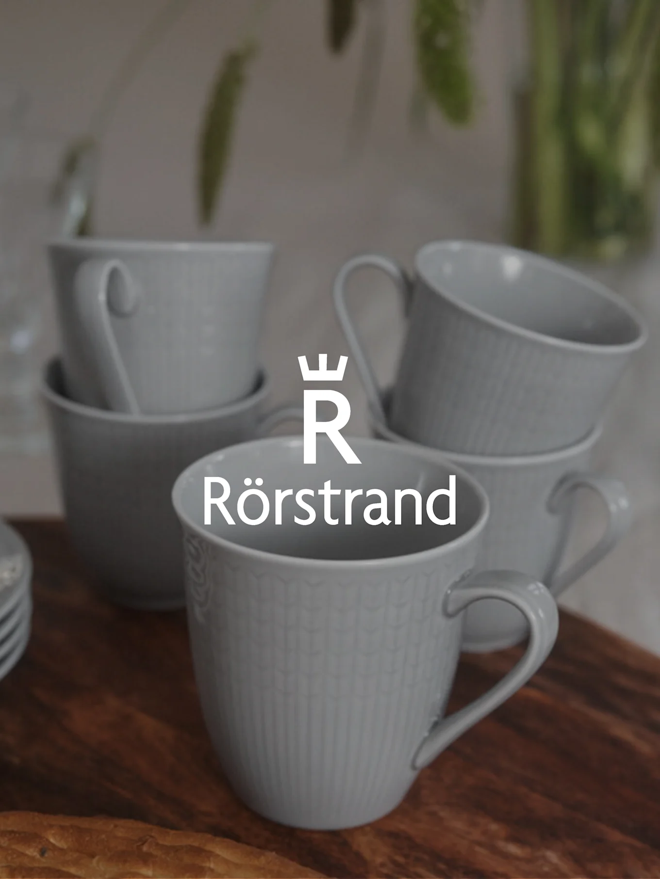 Rörstrand logo over light grey textured cups stacked on a wooden table.