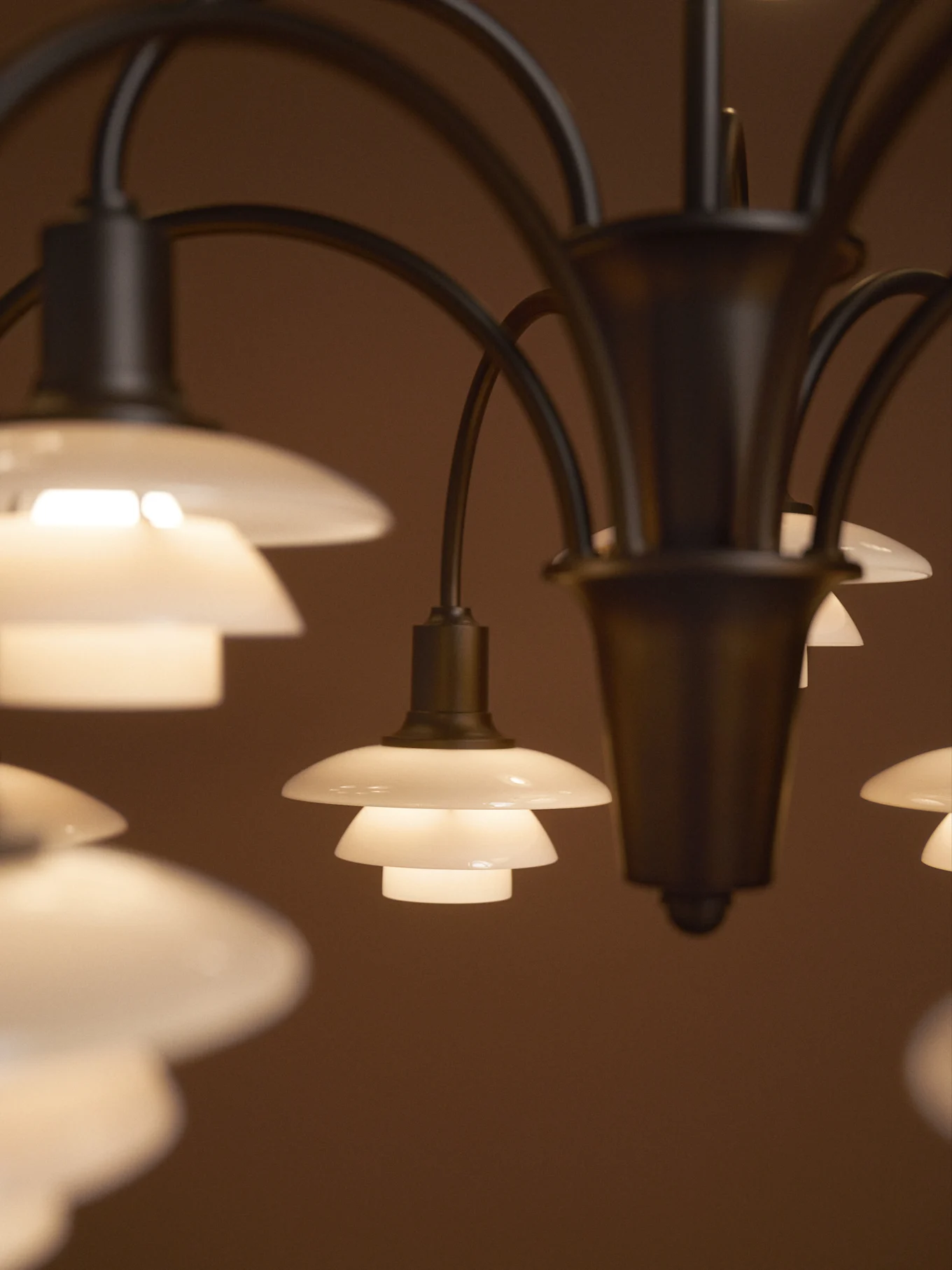 Chandelier with multiple glowing, tiered frosted glass shades against a dark background.