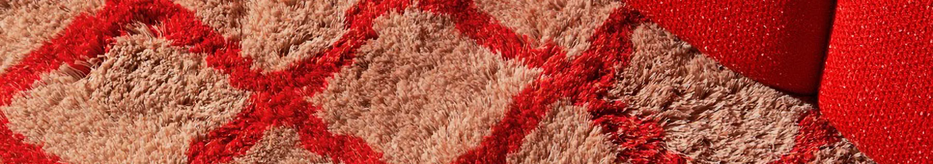 Shaggy rug with red geometric patterns on a beige background.