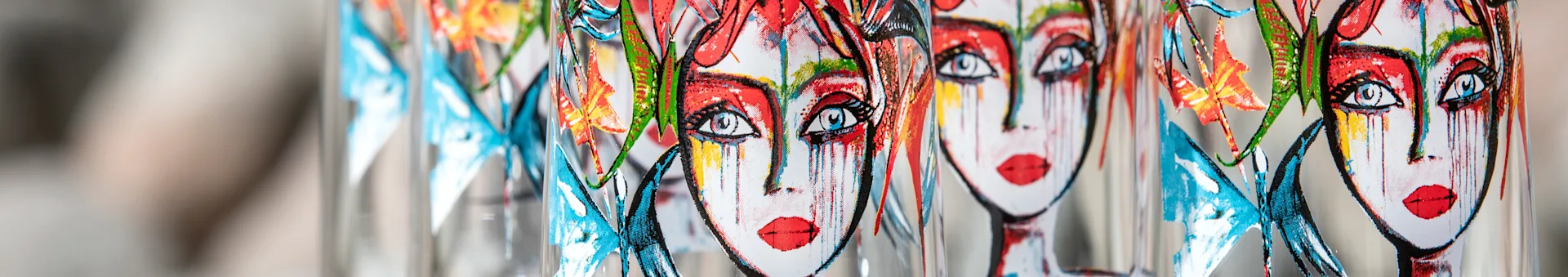 Close-up of multiple glass bottles or vases decorated with colorful pop-art faces and butterflies.