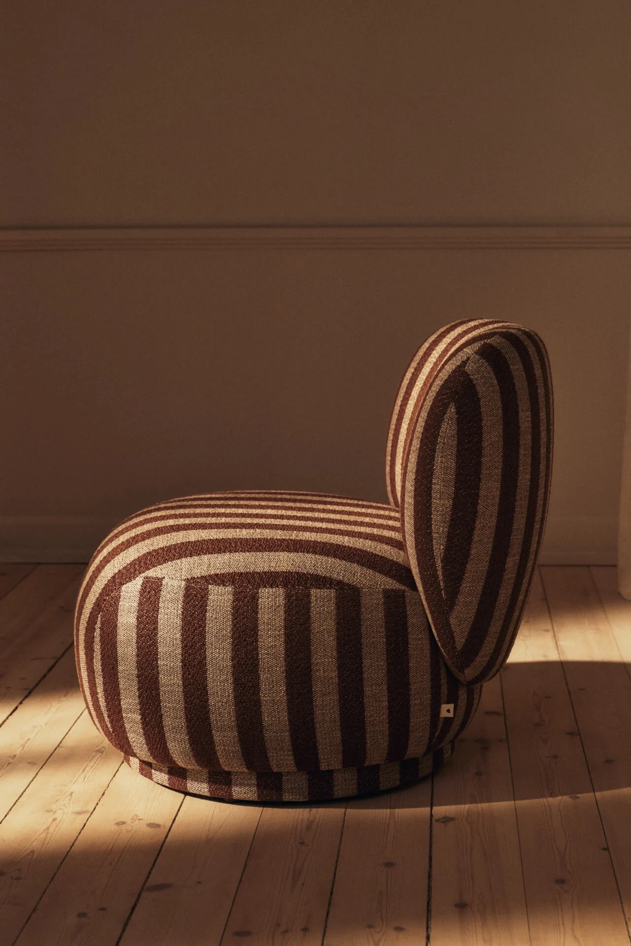 Rounded armchair with brown and beige stripes on a wooden floor.