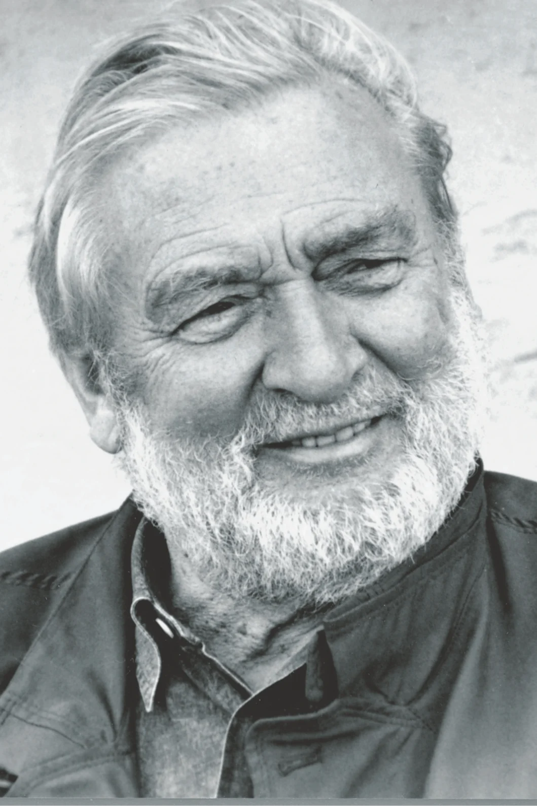 Black and white portrait of a smiling older man with a white beard and gray hair.