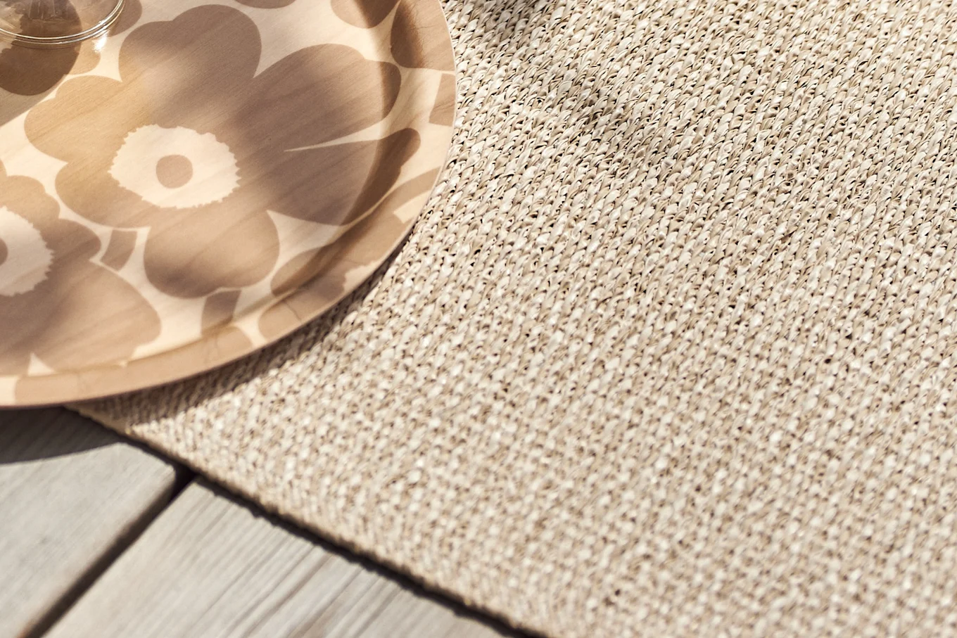 Floral patterned wooden tray on a woven mat and wooden deck.