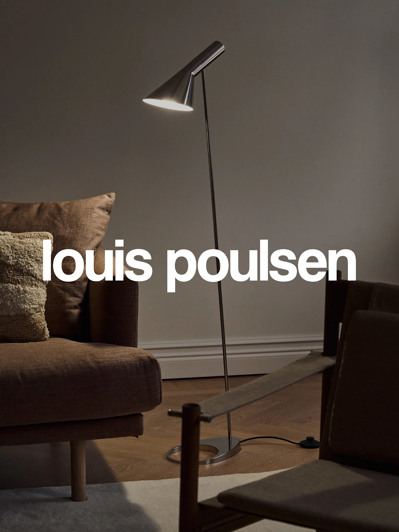 Modern floor lamp illuminating a cozy living room with a brown sofa and chair, featuring the Louis Poulsen logo.