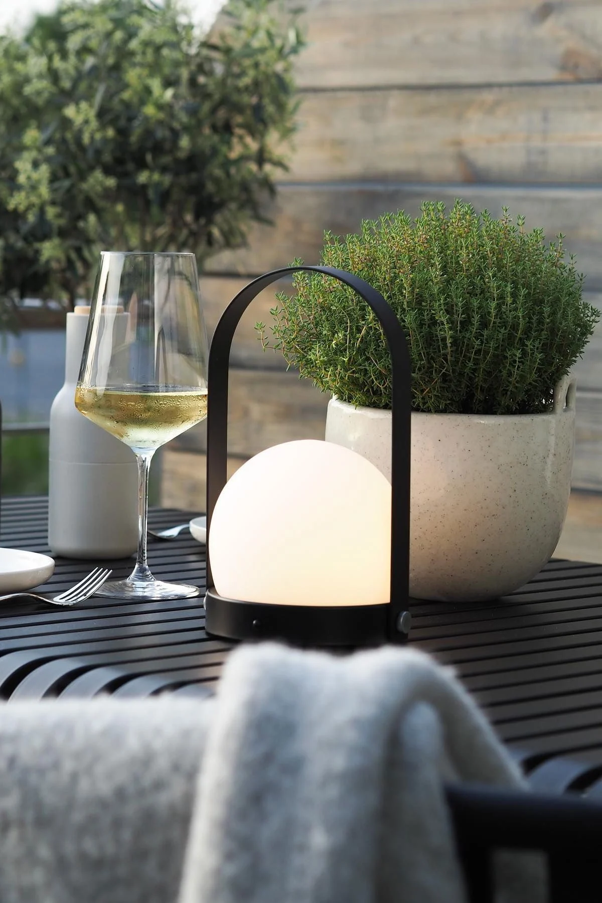 The portable Carrie lamp from Audo Copenhagen and the Speckle flower pot from Ferm Living stand on the Palissade table from HAY on @wohngluecksieben's terrace.