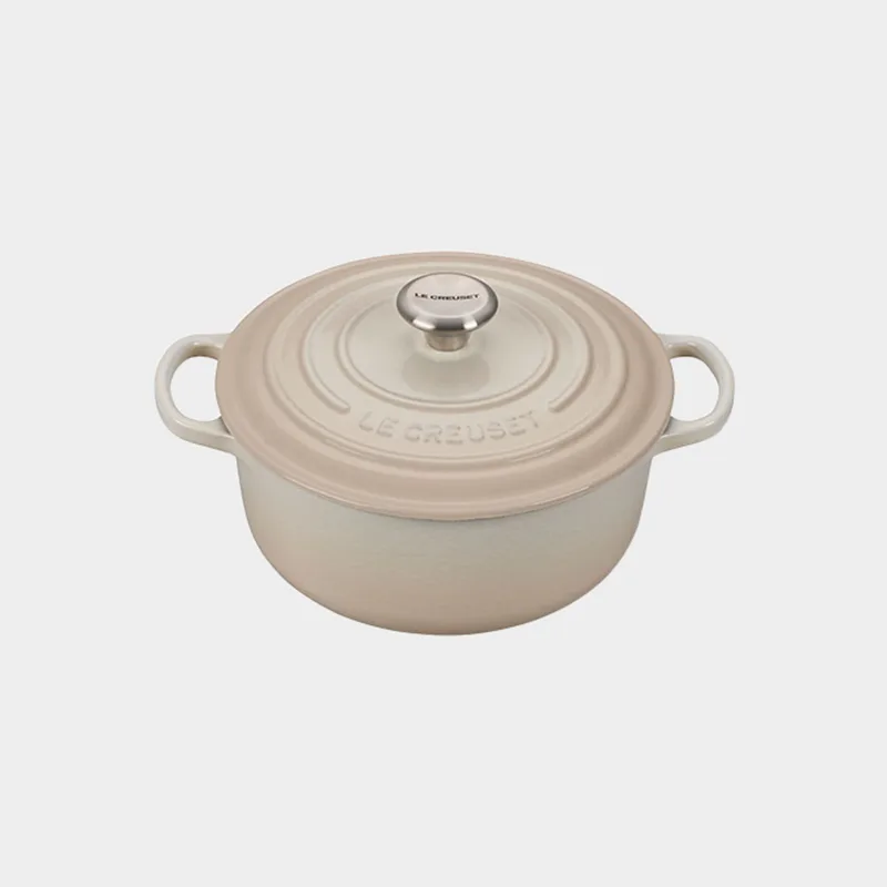 A round, shallow, beige Le Creuset Dutch oven with a matching lid and silver knob.