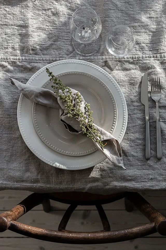Here you see a grey napkin folded into a rustic knot with a flower from the garden.