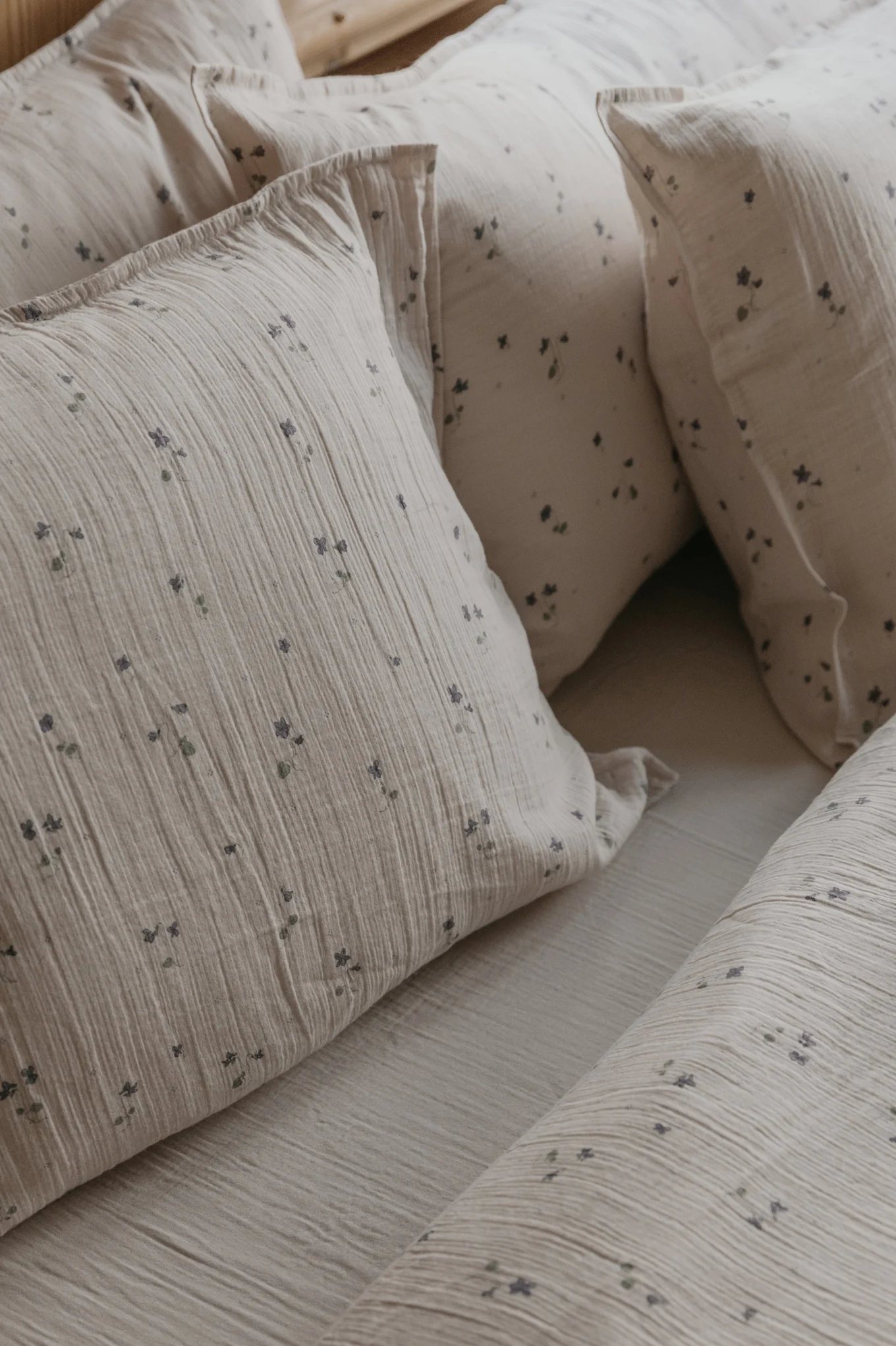 Light beige crinkled pillows and bedding with small blue floral patterns.