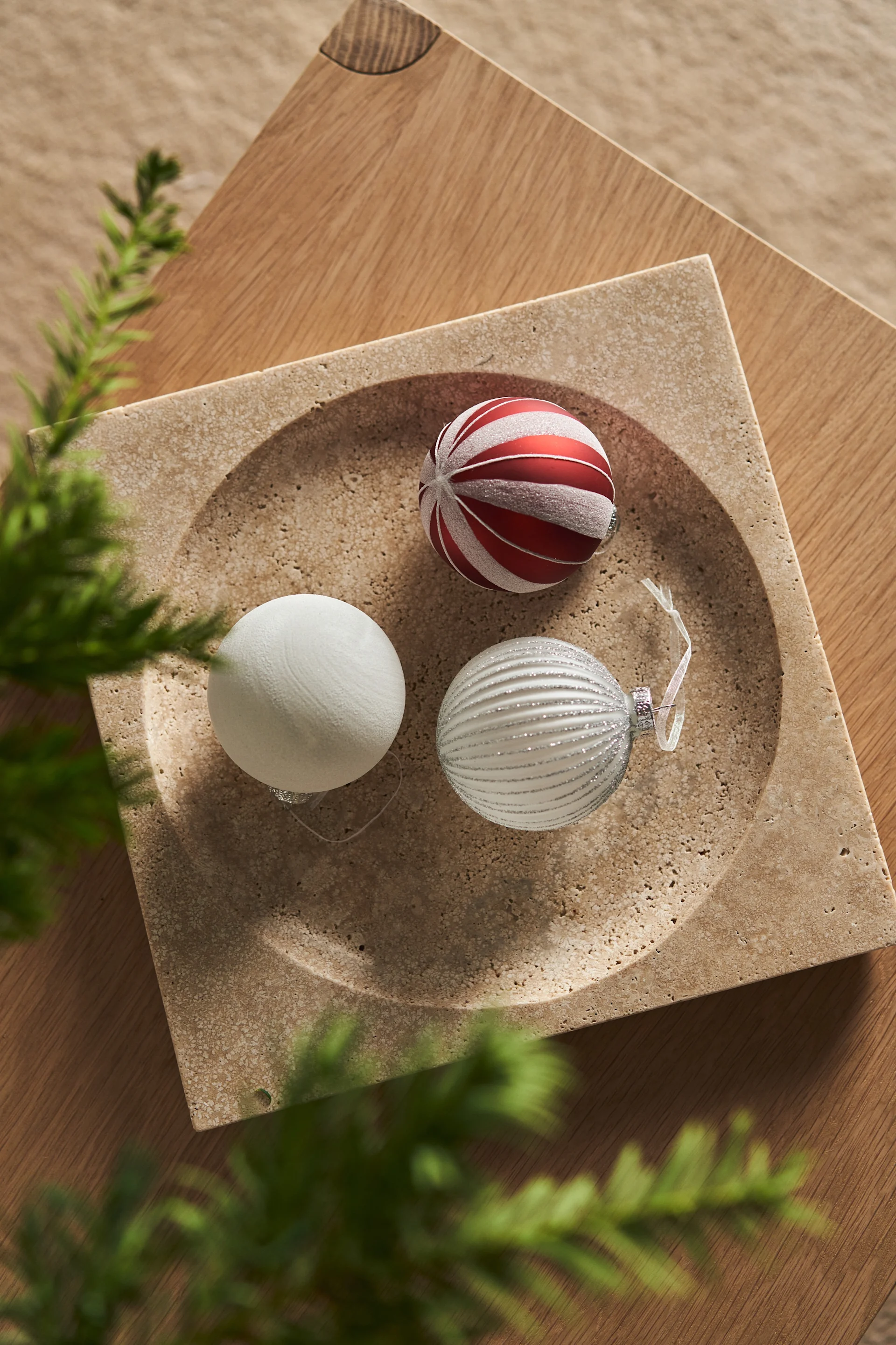 Various Christmas baubles by Scandi living are displayed as Christmas decorations on a table.