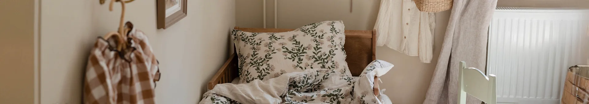 A bed with white floral bedding, a striped bag on a coat rack, and a radiator in a cozy room.
