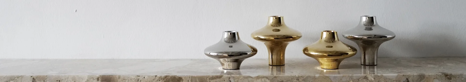 Four elegant metallic vases on a marble surface; two gold and two silver, each with a unique, bulbous design.