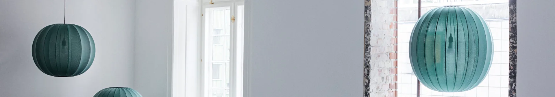 Teal oval pendant lamps in a white room.