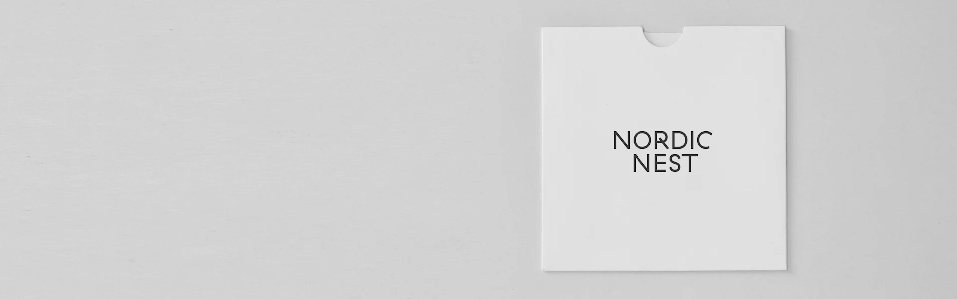 White card with 'NORDIC NEST' printed in black, on a light grey textured surface.
