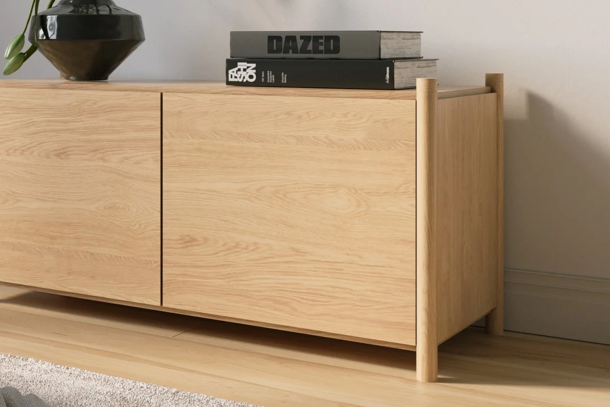 Light wood two-door cabinet with a black vase and two books on top.