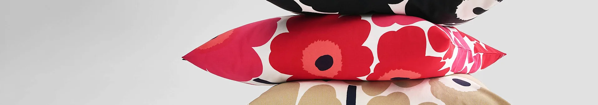 Stack of three pillows with floral patterns in black/white, red/pink, and tan/white.