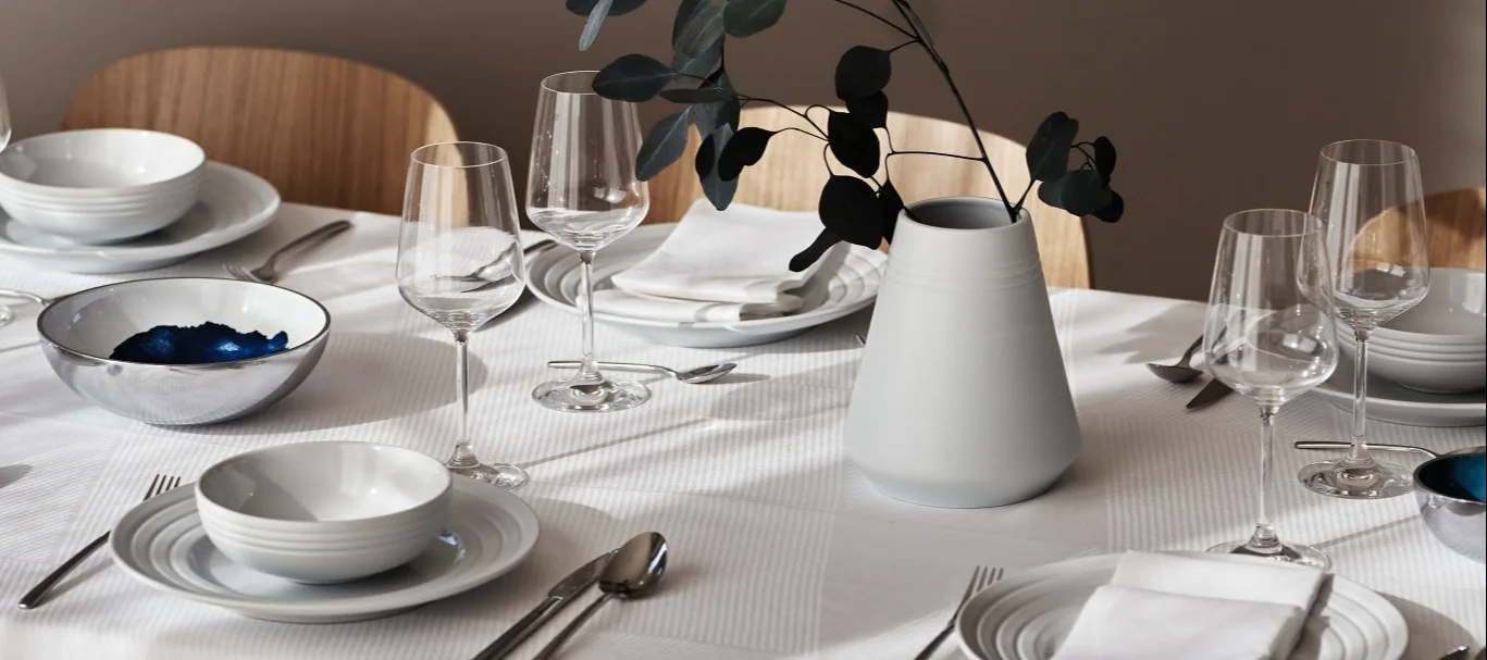 Wine glasses on a crisp white table setting with the NRJD plates and tableware.