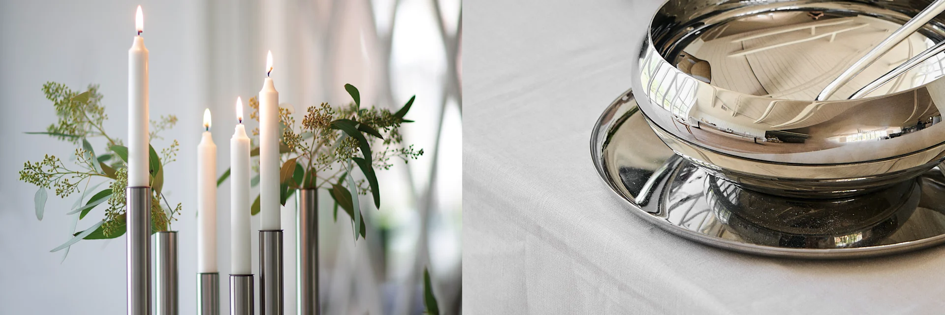 Decorated table with lit white candles and green foliage, alongside a shiny silver bowl and tray.