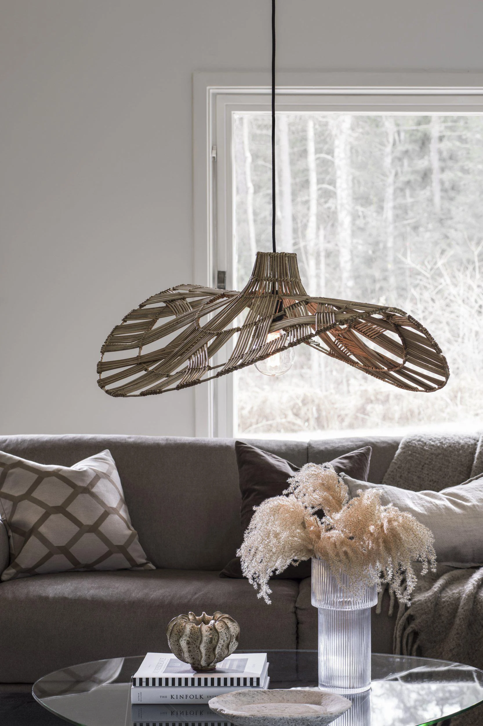 A large, organic-shaped pendant light with a woven rattan shade hangs over a living room sofa.