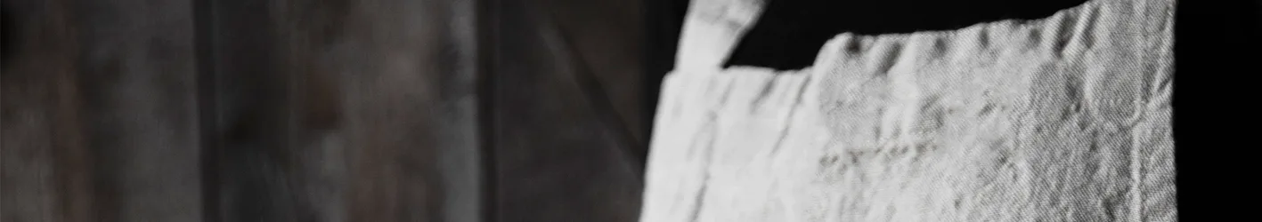 Close-up of light-colored, textured fabric with visible stitching.