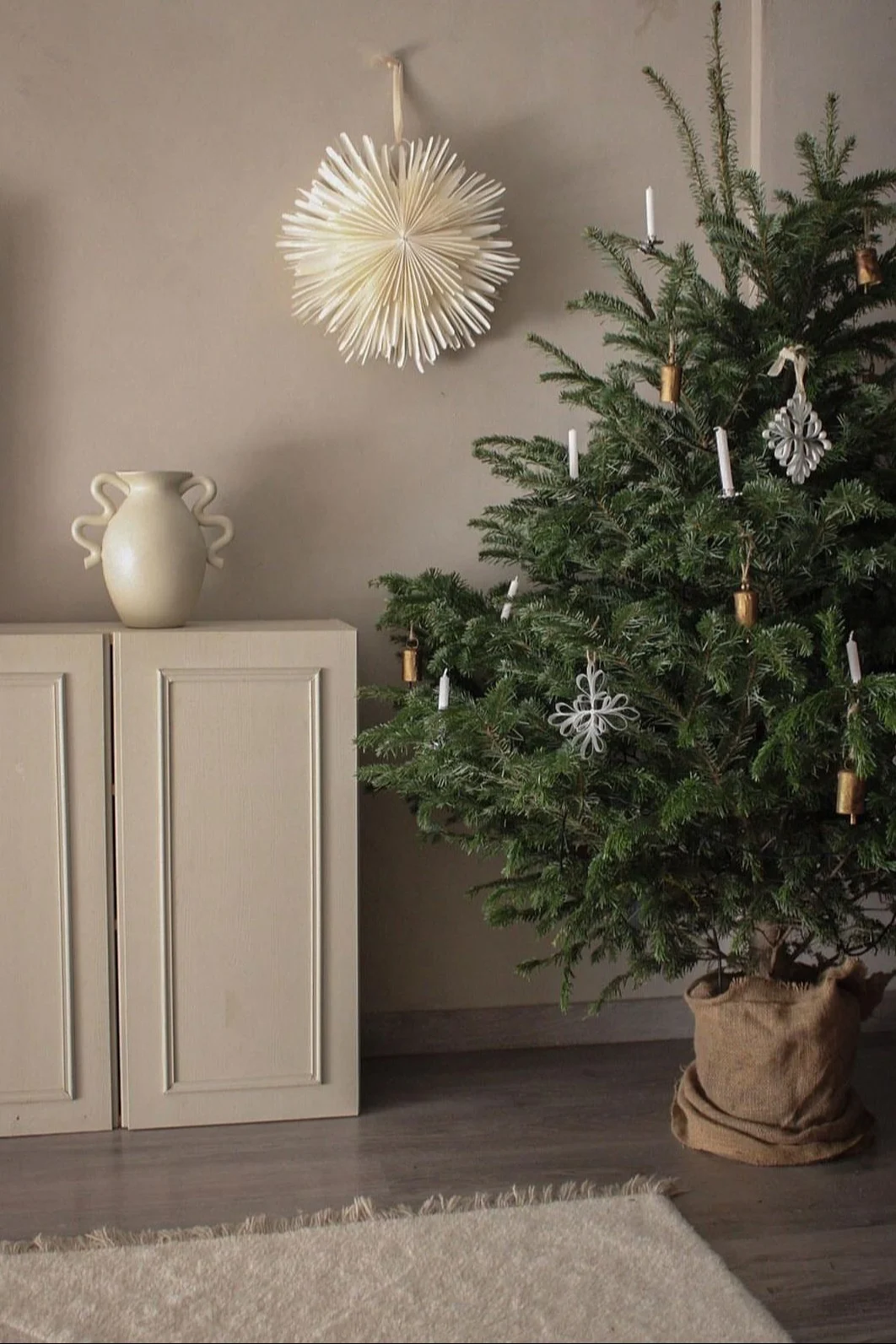Minimalist Christmas decor like the Oslo paper Christmas star from Watt & Veke. Seen here hanging in the window of a neutral coloured living room. 