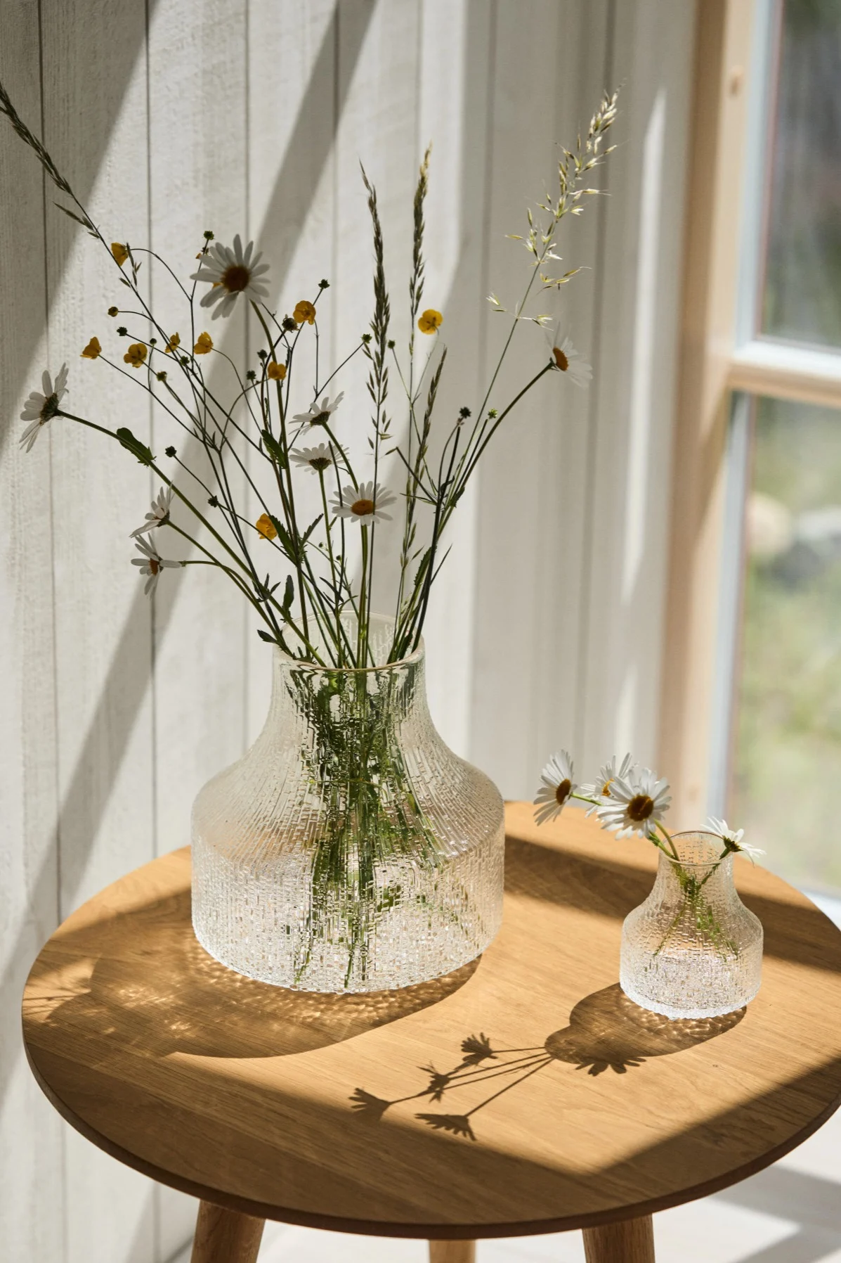 The best vase for small bouquets and individual flowers is a small or a mini vase like the Ultima Thule vases you see here in the sunshine on a table. 