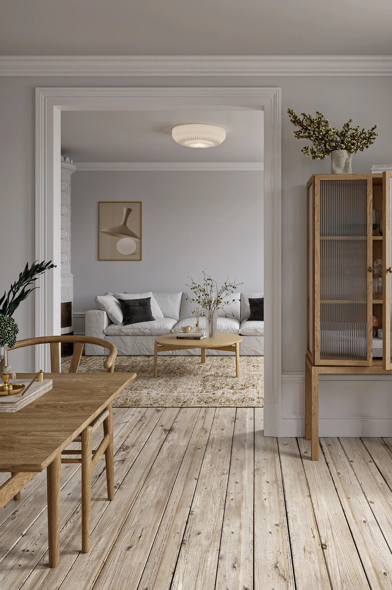 A minimalist living room with a white sofa, round wooden coffee table, and a wooden cabinet with fluted glass doors.