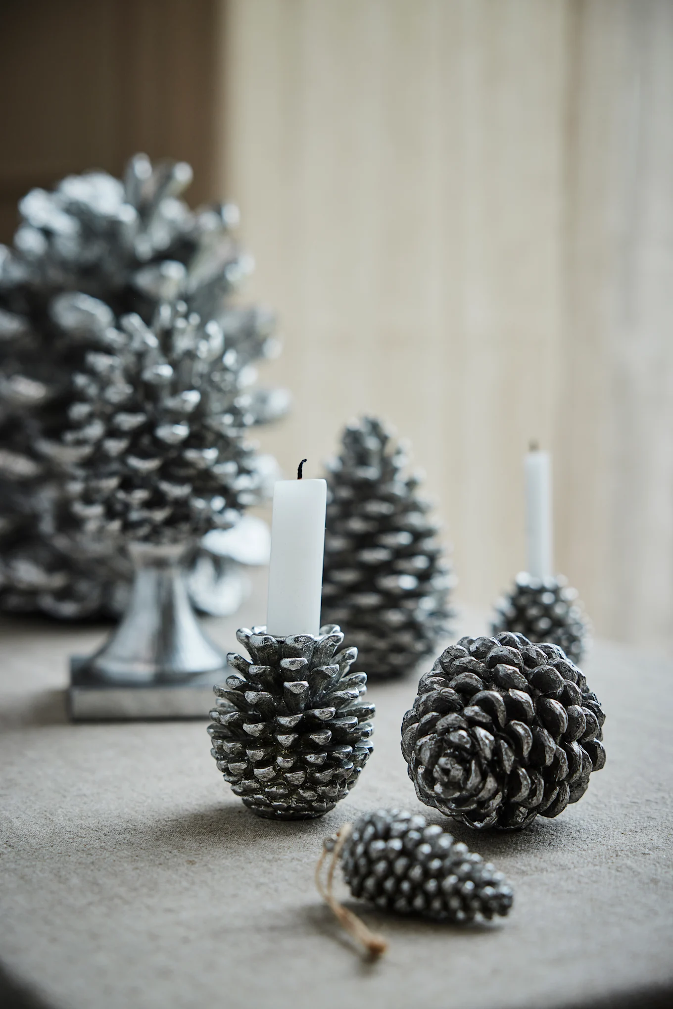 Several silver pine cones by Lene Bjerre lie on a table and are the perfect Christmas decoration for 2025.