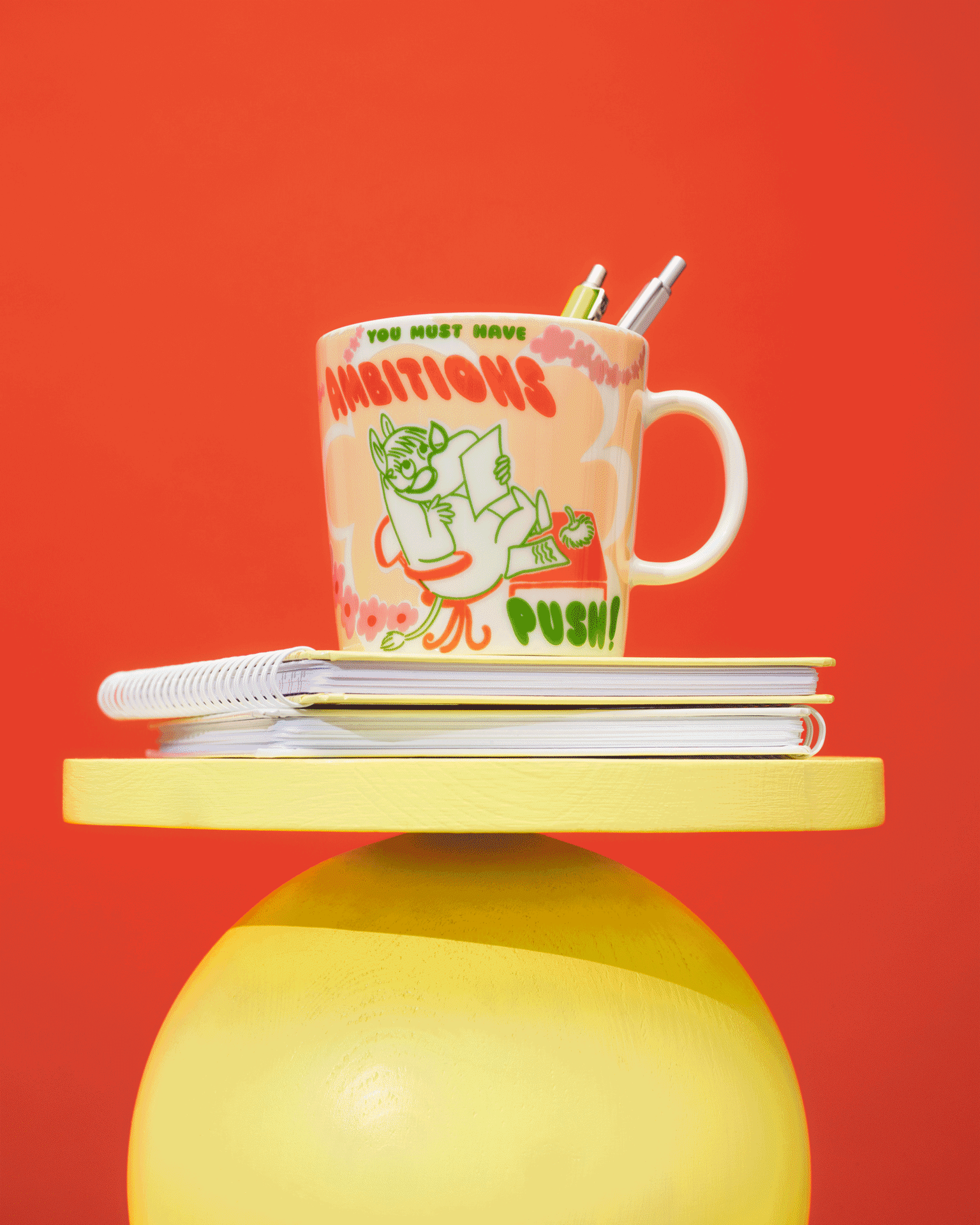 Four colorful Moomin-themed mugs on yellow and red tiered displays against a red background.