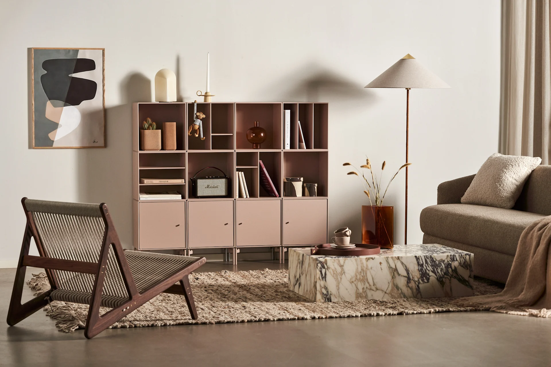 A modern living room with a pink modular shelf, marble coffee table, brown sofa, wooden chair, and a framed abstract art piece.