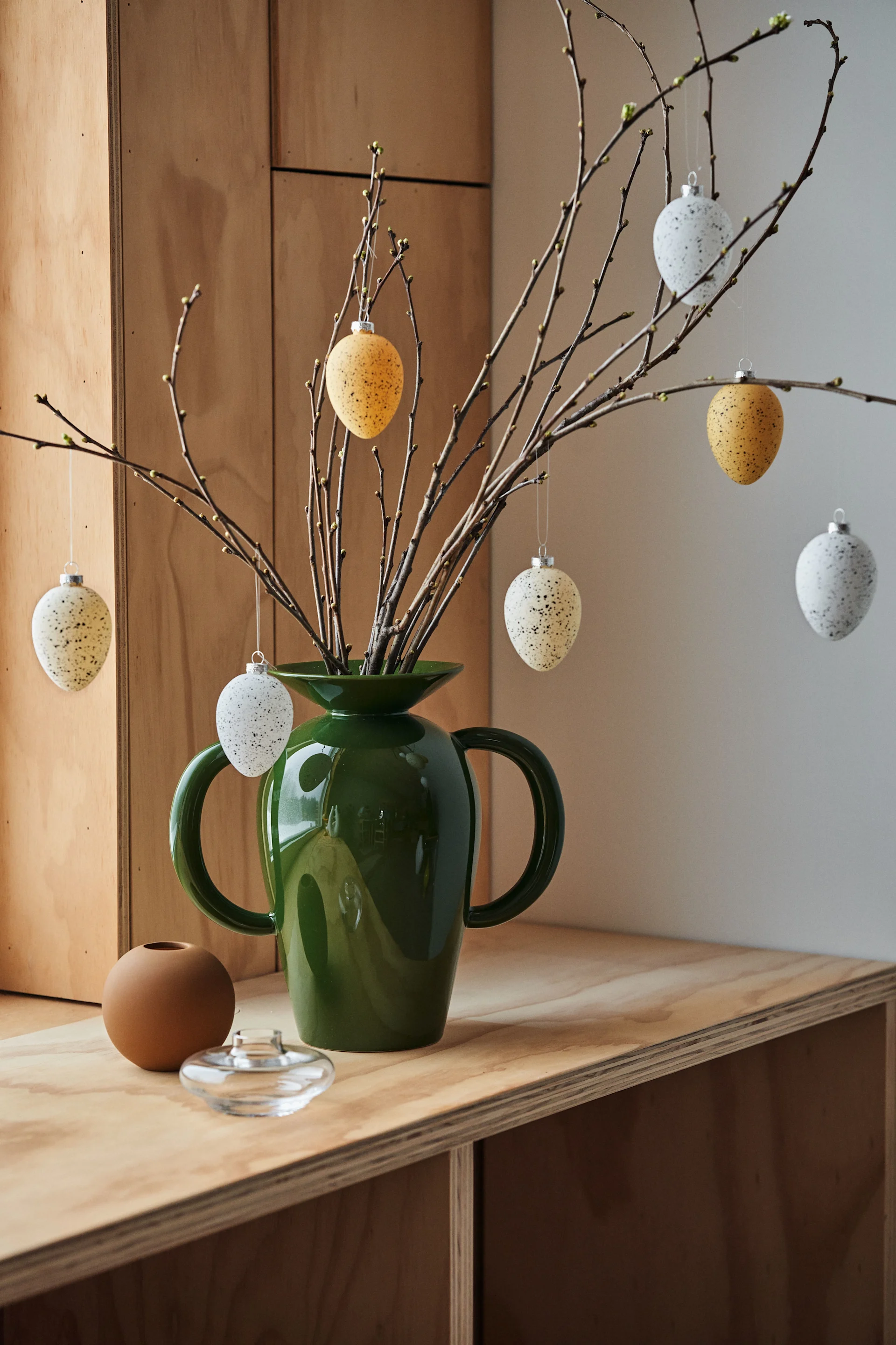 An Easter tree on a table in the Momento vase from &Tradition, decorated with Brooding glass eggs from Scandi Living.