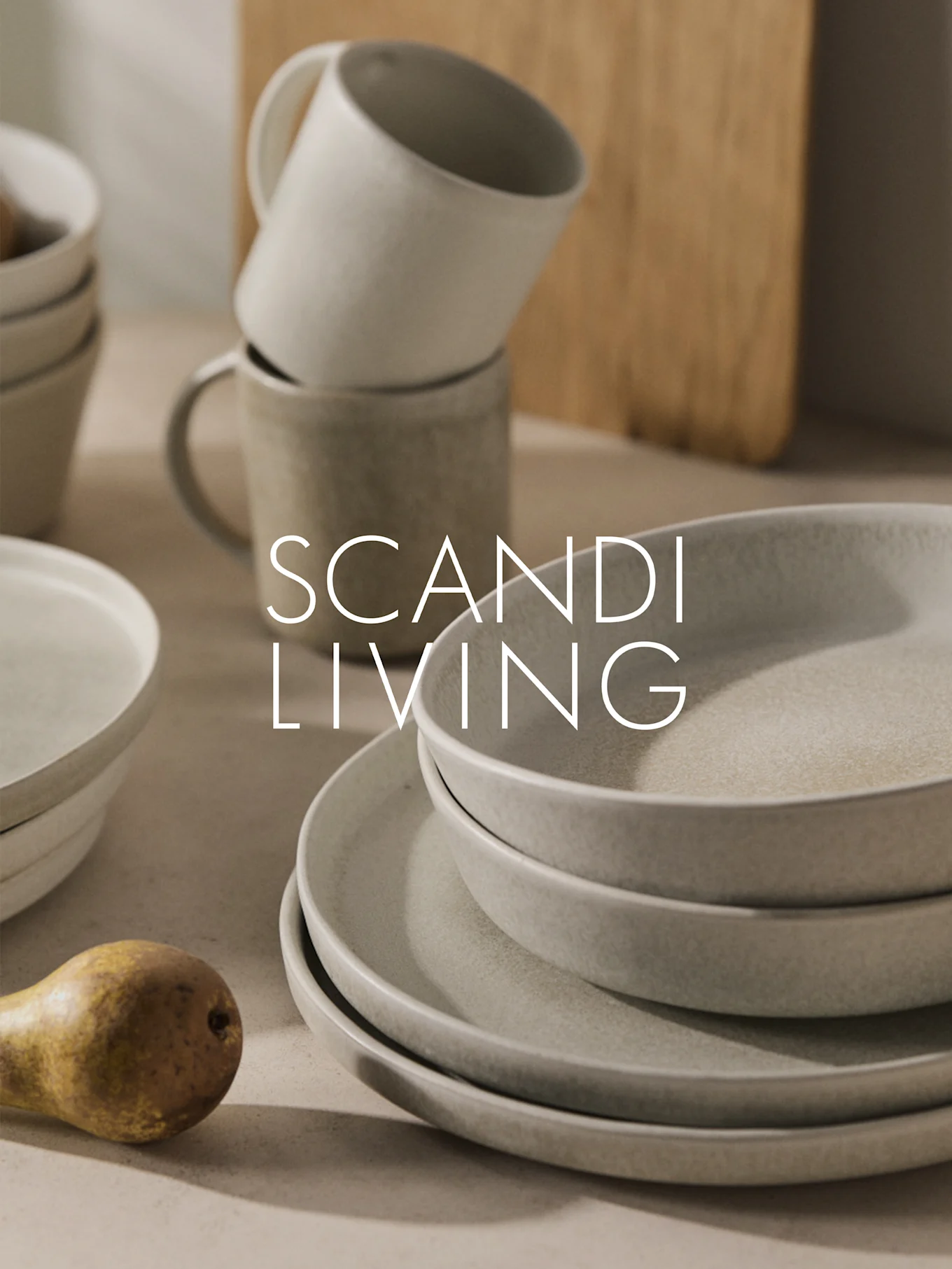 Stacked beige ceramic dinnerware, mugs, and a pear with "SCANDI LIVING" overlay.
