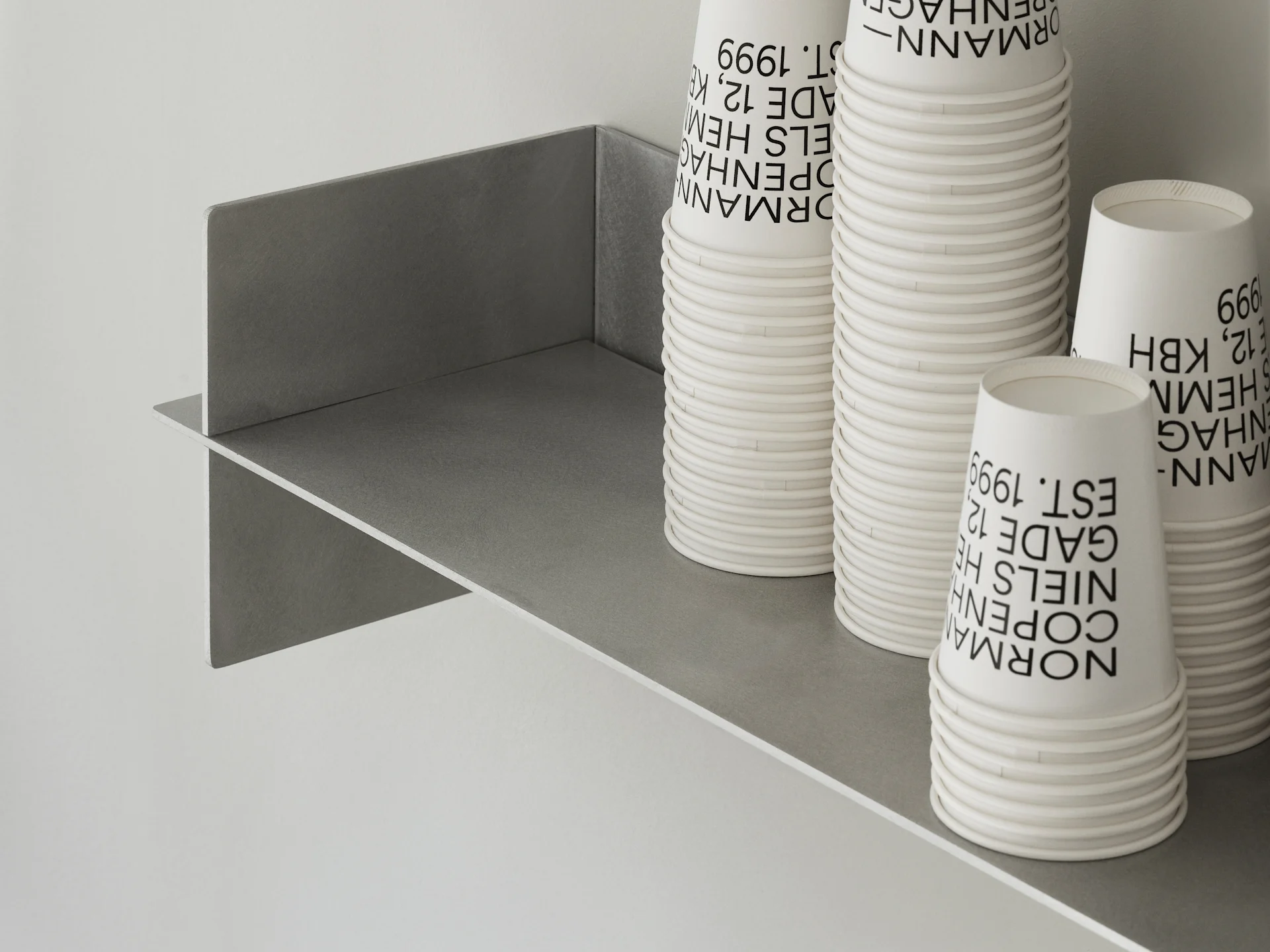 Stacked white paper cups with black text on a gray shelf.