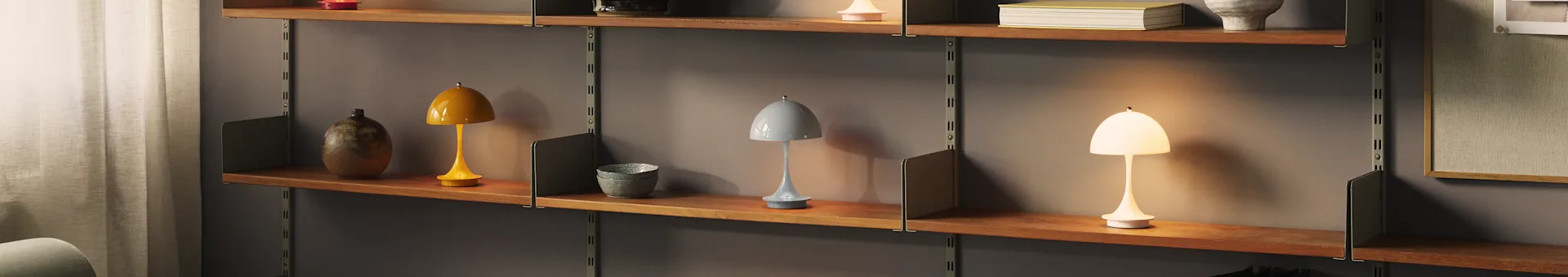 Three mushroom-shaped portable lamps on a wooden shelf: yellow, light blue, and an illuminated white one.