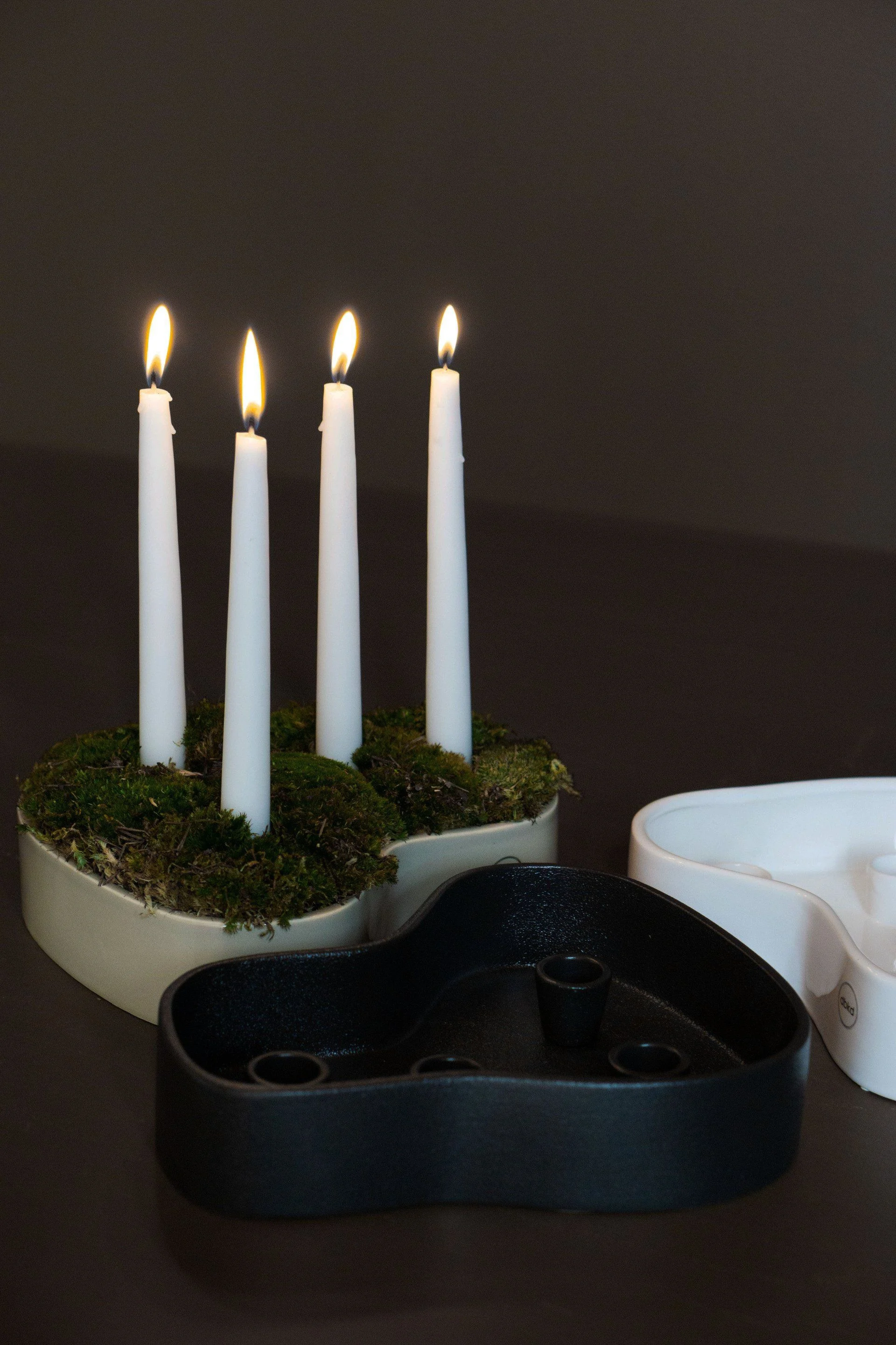 An asymmetrically shaped candle holder with four real lit candles