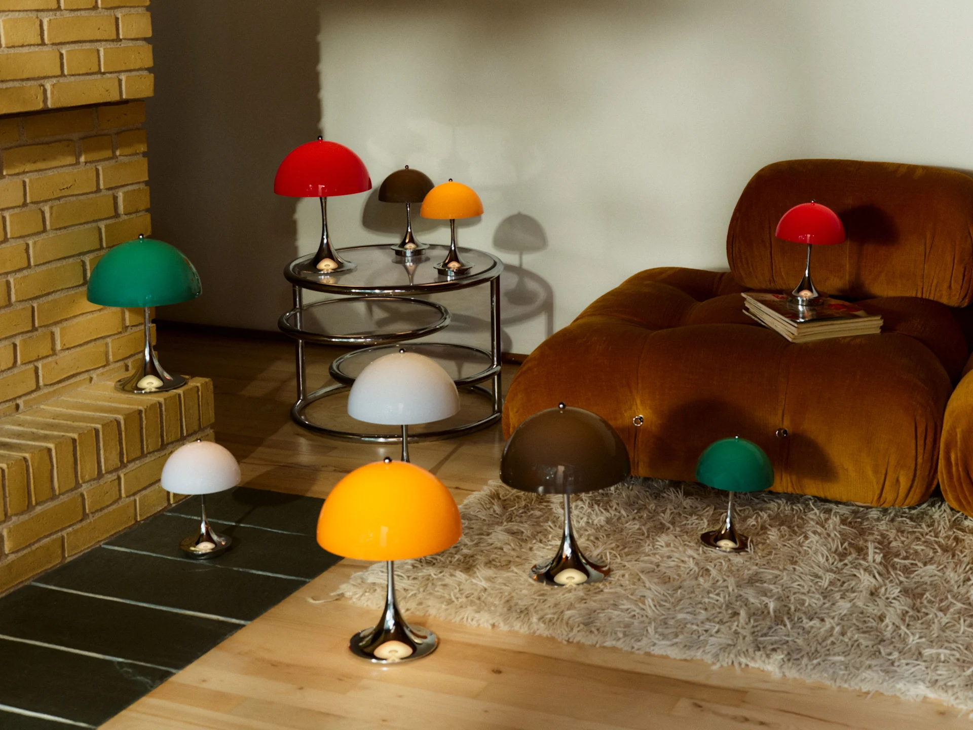 A collection of mushroom-shaped table lamps in red, green, white, yellow, and brown, with silver bases, arranged in a cozy living room.