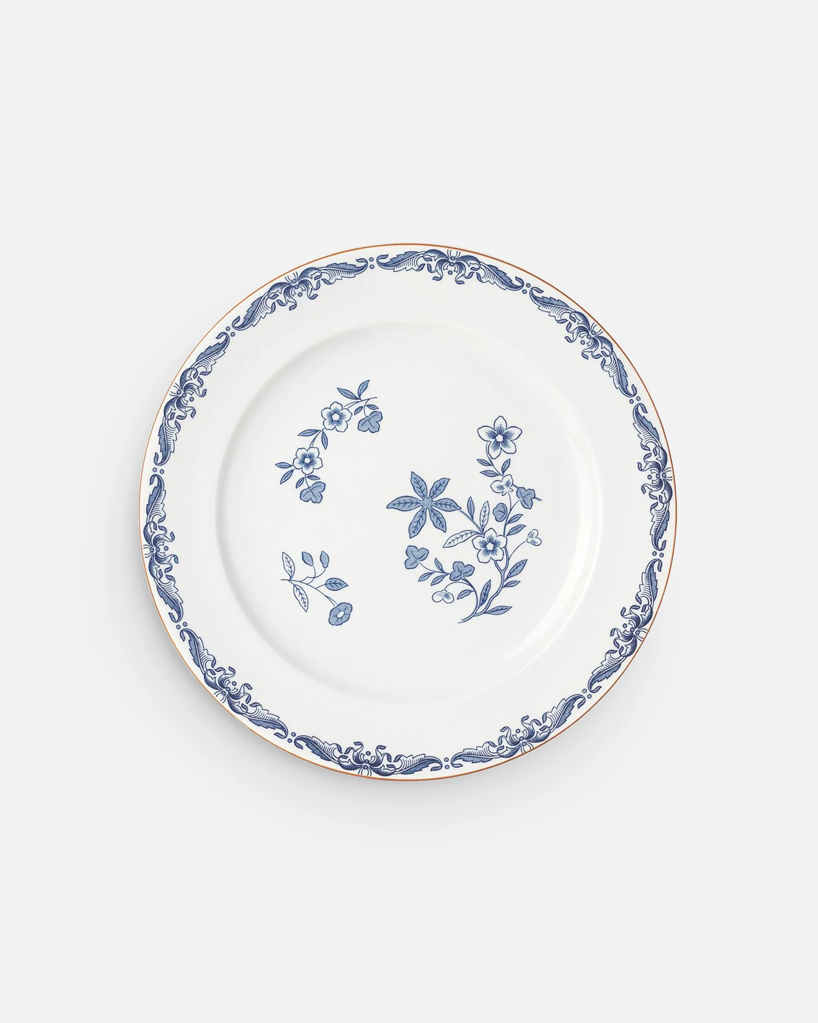 White plate with blue floral pattern in the center, a blue scroll border, and a gold rim.
