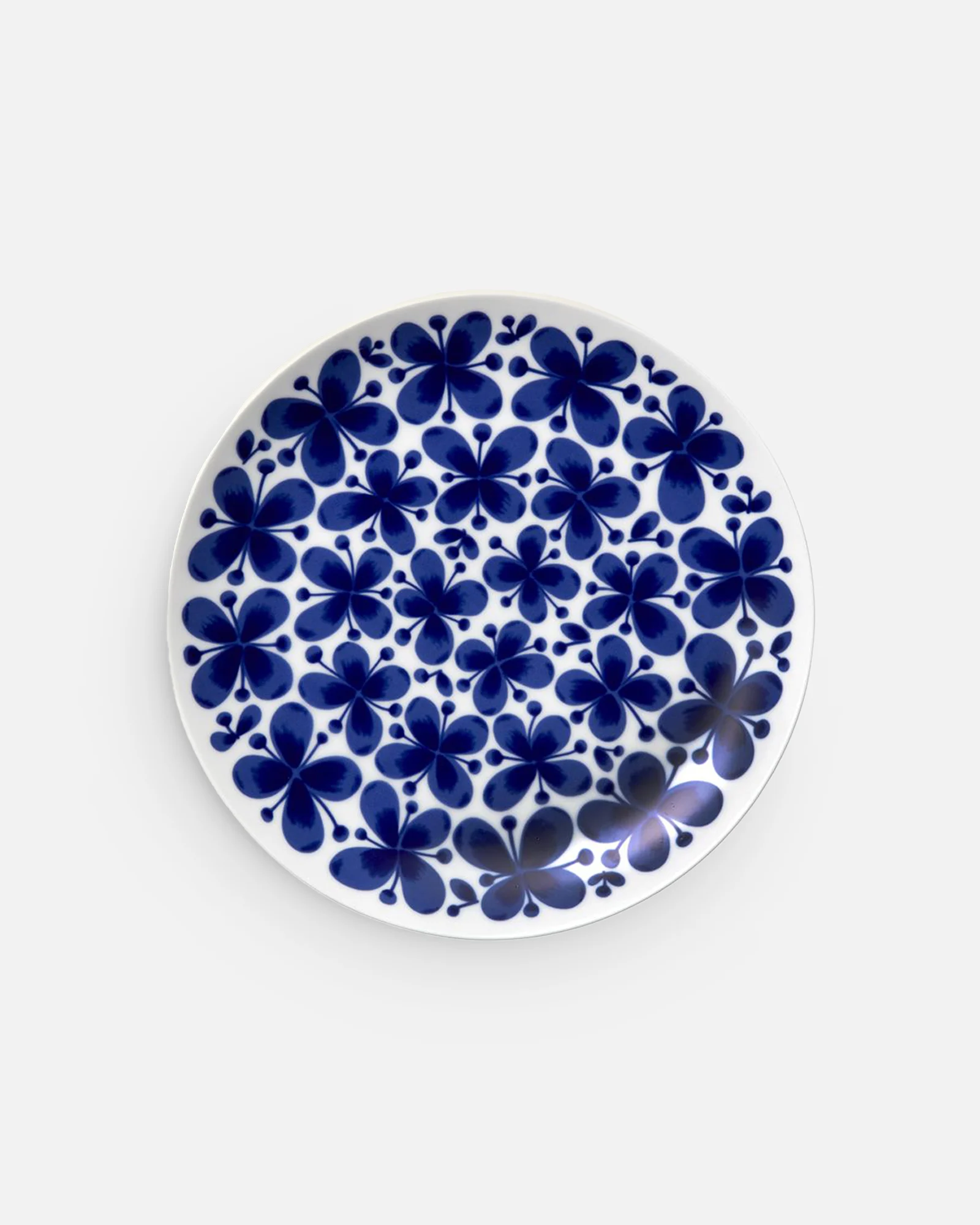 White round plate with a repeating dark blue floral pattern.