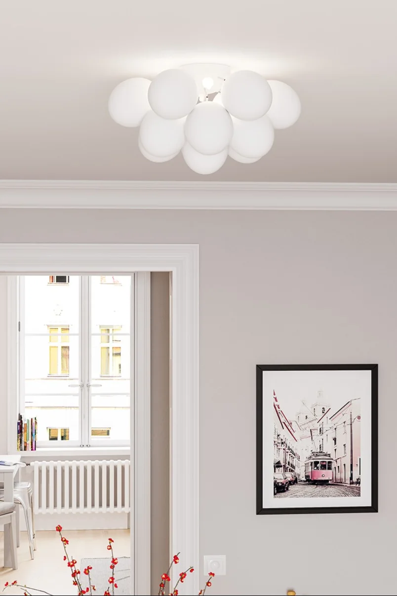 Modern ceiling light with a cluster of white spherical shades, illuminating a light-colored room with a framed art print on the wall.