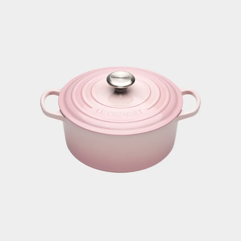 Light pink cast iron Dutch oven with a matching lid and silver knob, seen from an elevated angle.