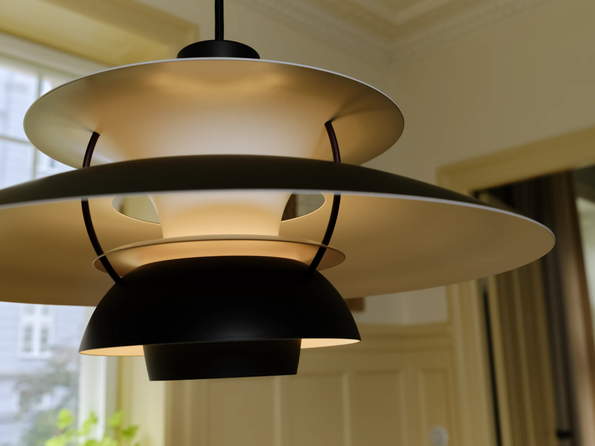 Modern multi-layered pendant lamp with black and light-colored concentric shades, emitting a warm glow.