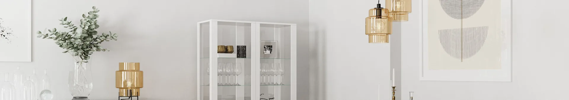 A modern room featuring a white glass cabinet, golden glass lamps, clear glass vases with eucalyptus, and framed abstract art.