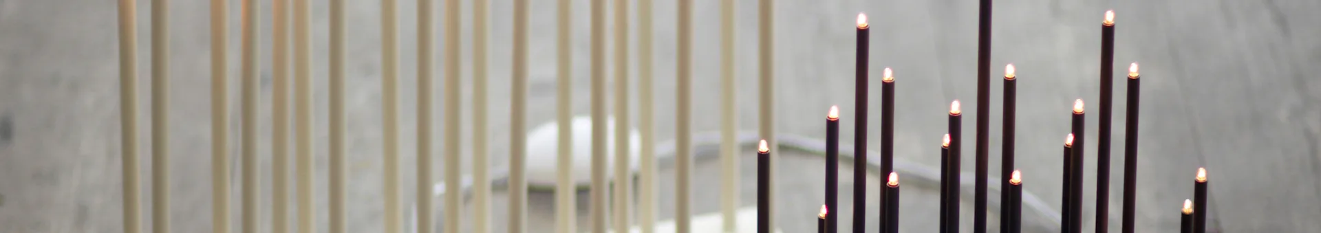 A row of light-colored vertical rods to the left, and dark electric candles with glowing tips to the right.