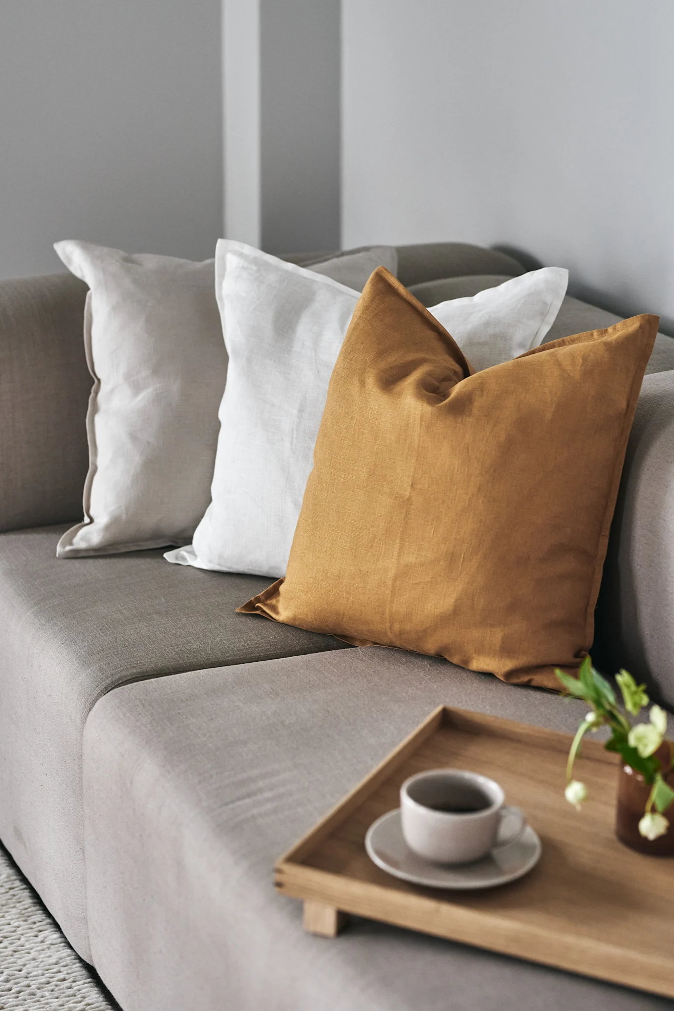 A mustard yellow cushion adorning a sofa with other cushions that reflect the colour trends of 2026.