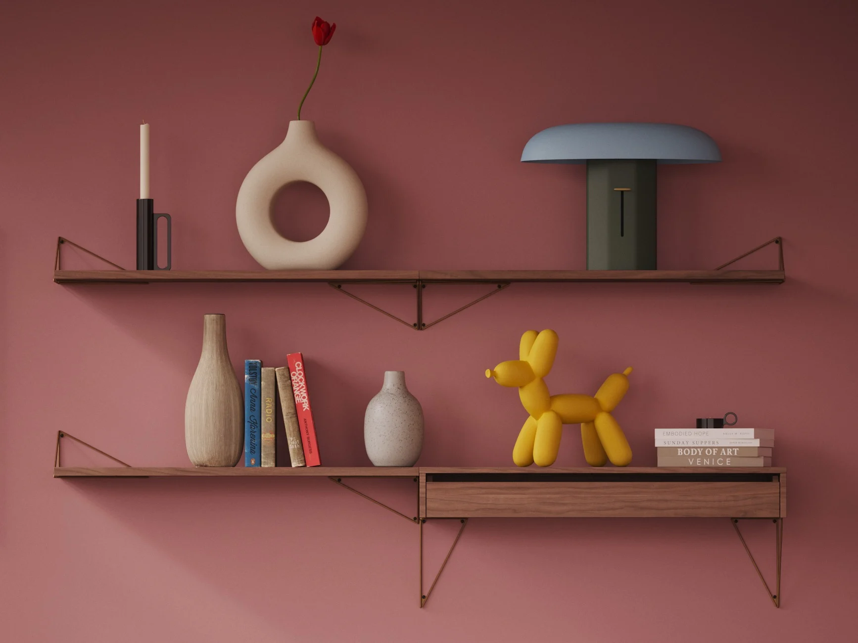 Two wooden shelves on a pink wall display various decorative objects: a candle, vases, books, a blue and green lamp, and a yellow balloon dog.