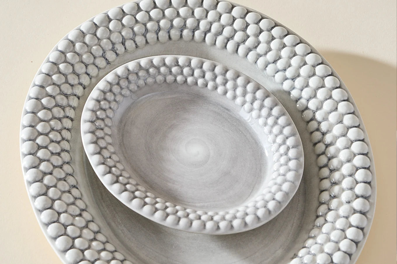 Two nested oval grey platters with textured, raised dot rims.