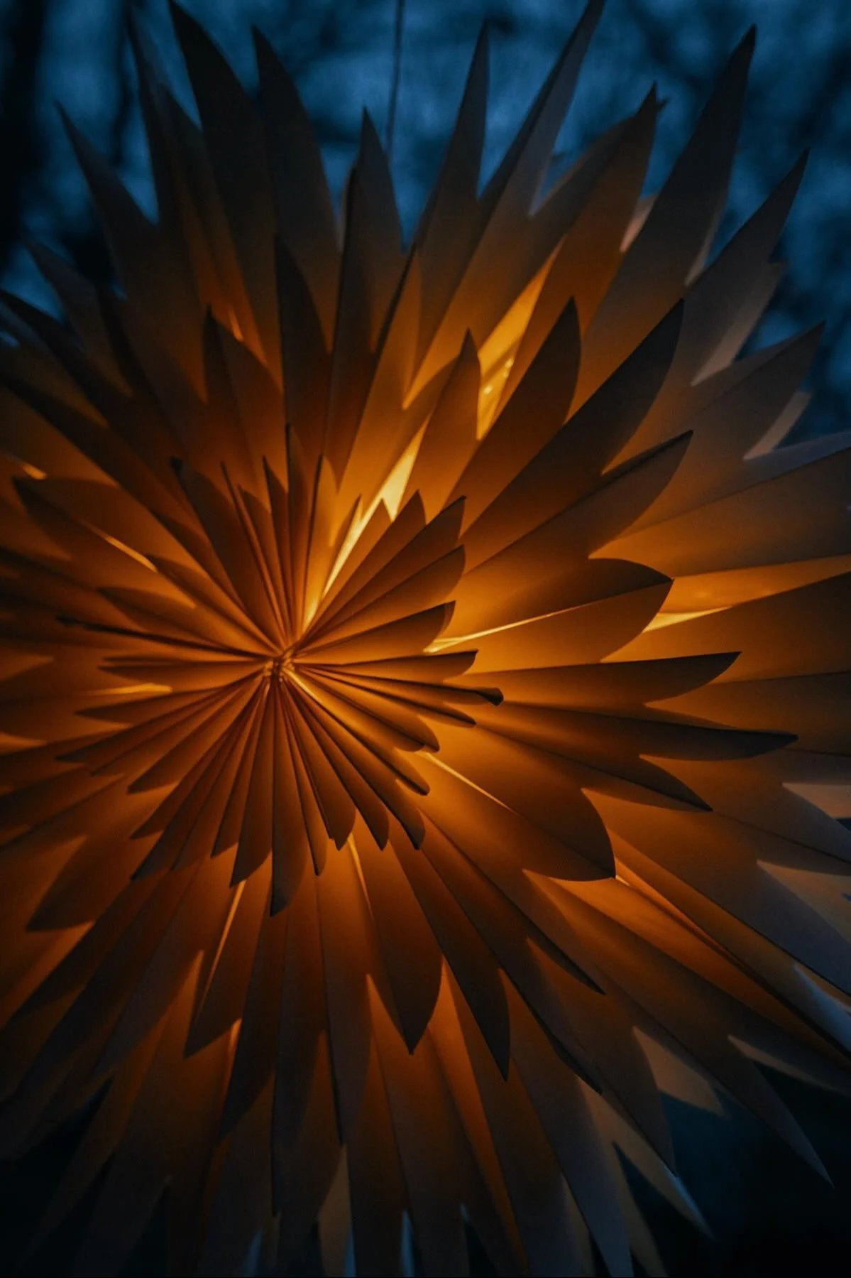 Paper star lantern with a warm golden glow against a dark blue background.