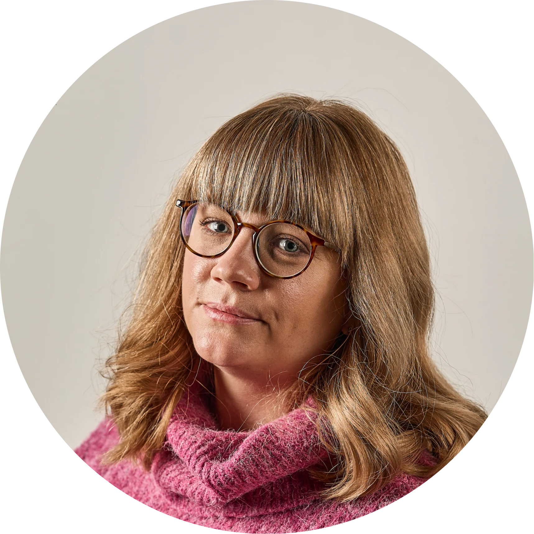 Woman with blonde hair, bangs, and tortoise-shell glasses wearing a pink knit turtleneck.