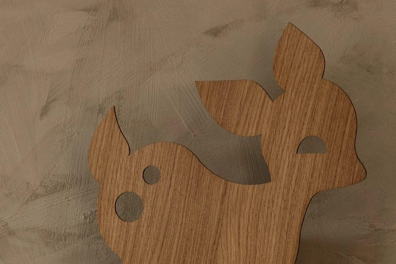 Wooden deer cutout with spots against a textured brown background.