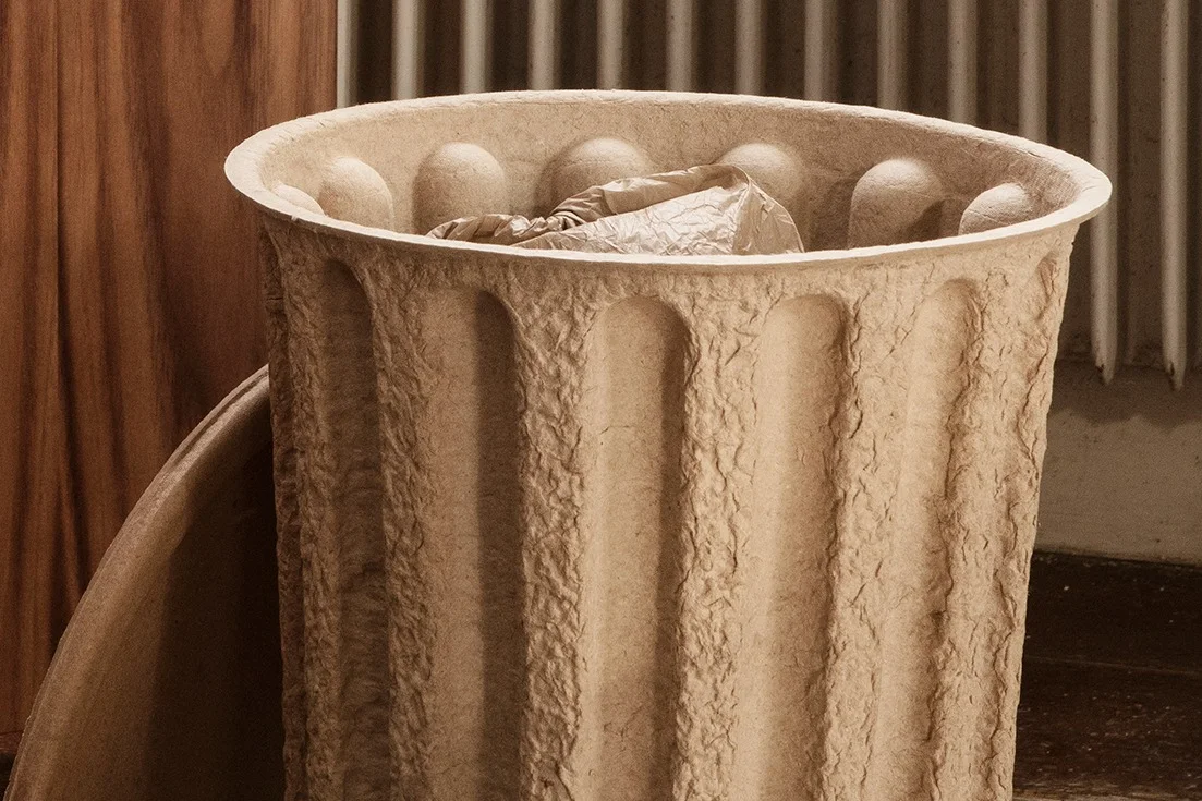 Close-up of a large, light brown fluted paper pulp container with crumpled material inside.