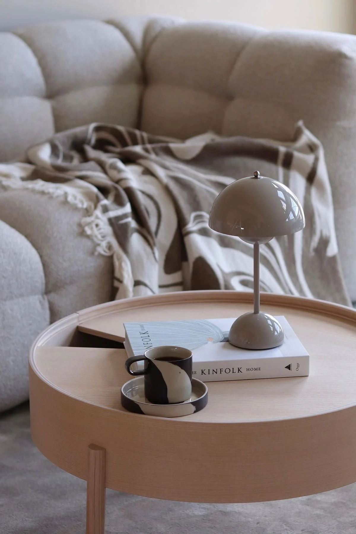A wooden coffee table is decorated with a book, a Flowerpot table lamp by &Tradition and the Inlay cup by Ferm Living.